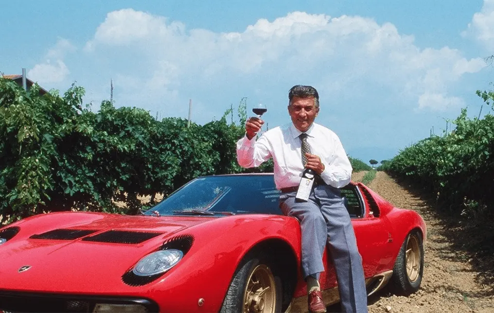 男性がランボルギーニの元でグラスワインを持ちポーズをとっています。